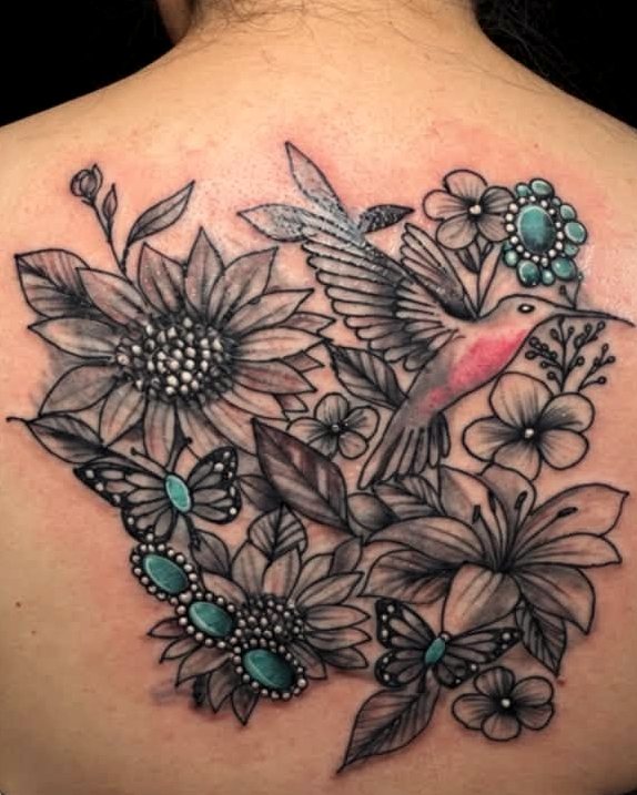 Black-and-grey back piece - a hummingbird among sunflowers and lilies, picked out with turquoise stones.
